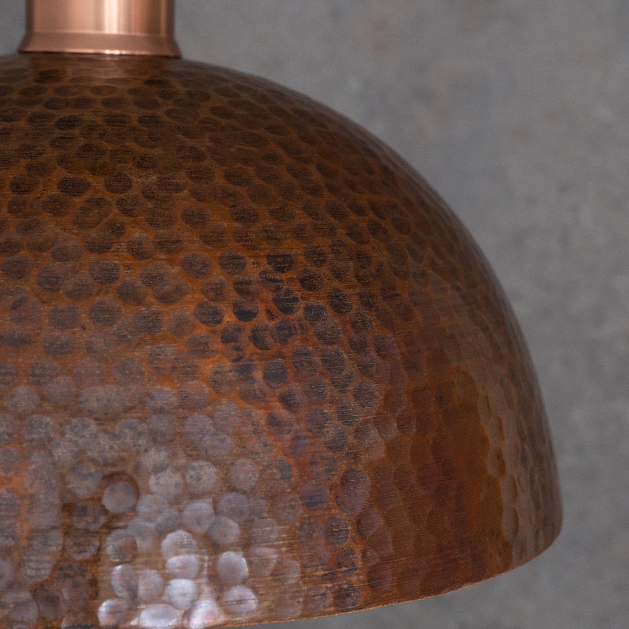 Close-up of hand hammered pendant light surface, deep irregular marks from individual artisan hammer strokes