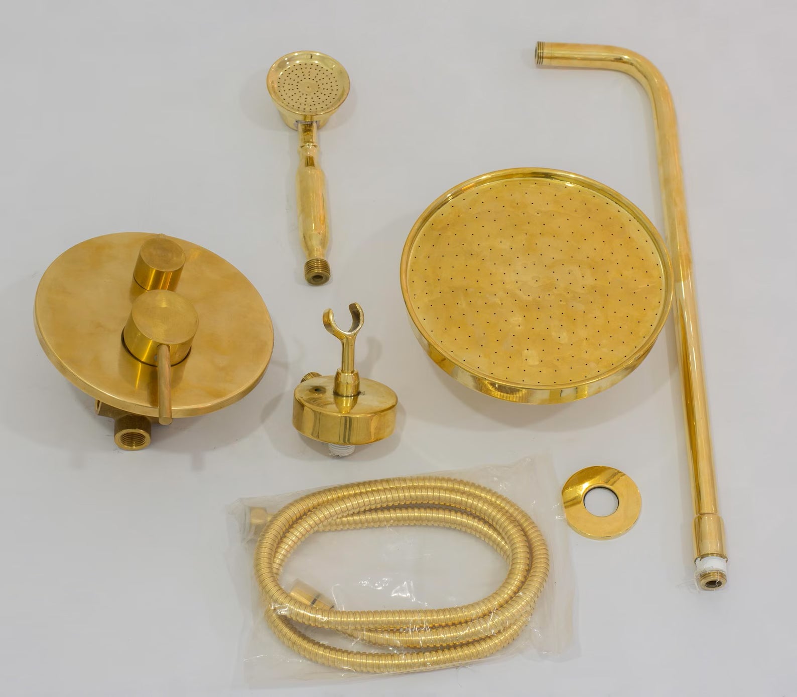 All pieces of the brass concealed shower system laid out: rain head, arm, mixer, handheld, hose and holder