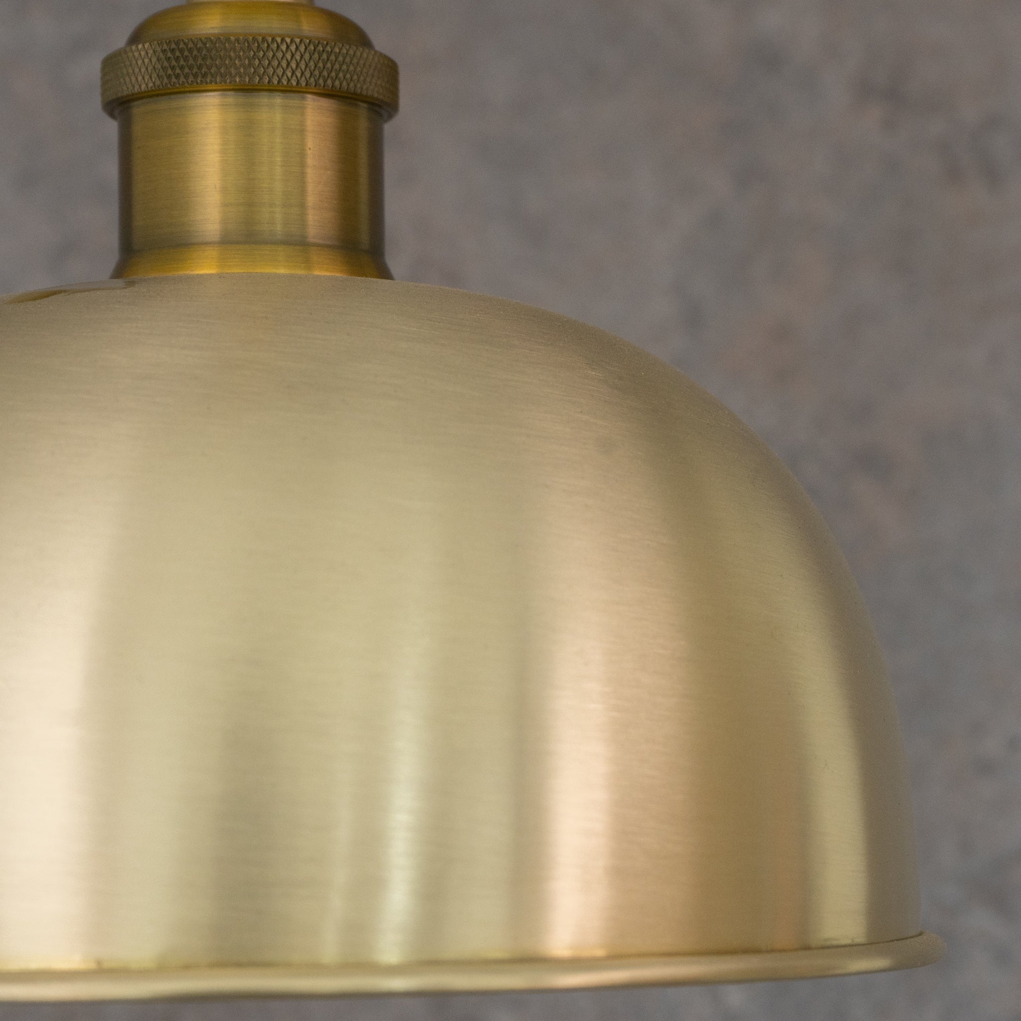 Close-up of brushed brass pendant light surface, smooth directional finish, no hammering