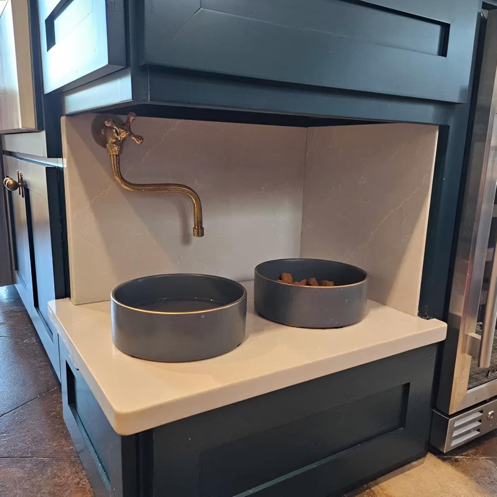 Insideast unlacquered brass pot filler installed in a real kitchen, wall-mounted with articulating swivel arm above the cooktop