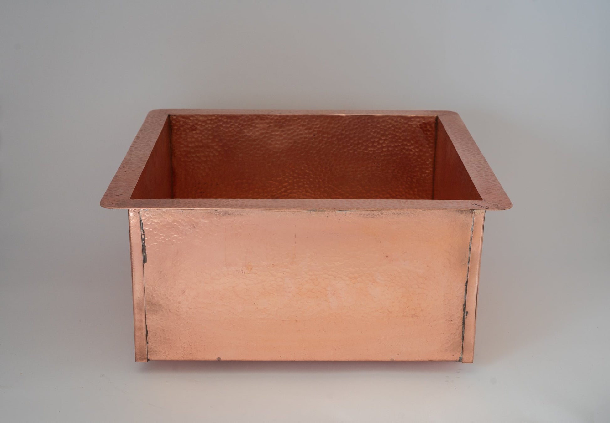 Copper hammered undermount sink installed in marble kitchen — profile view