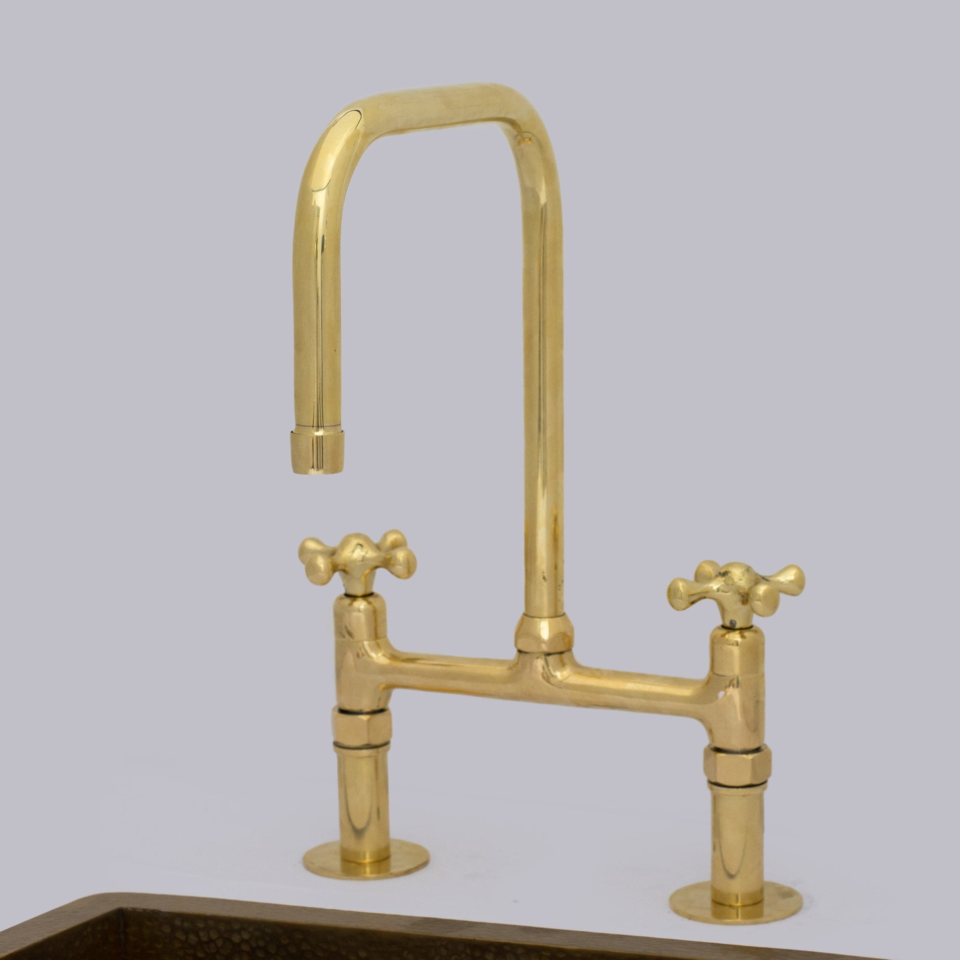 Unlacquered brass straight spout bridge faucet on a ceramic undermount sink