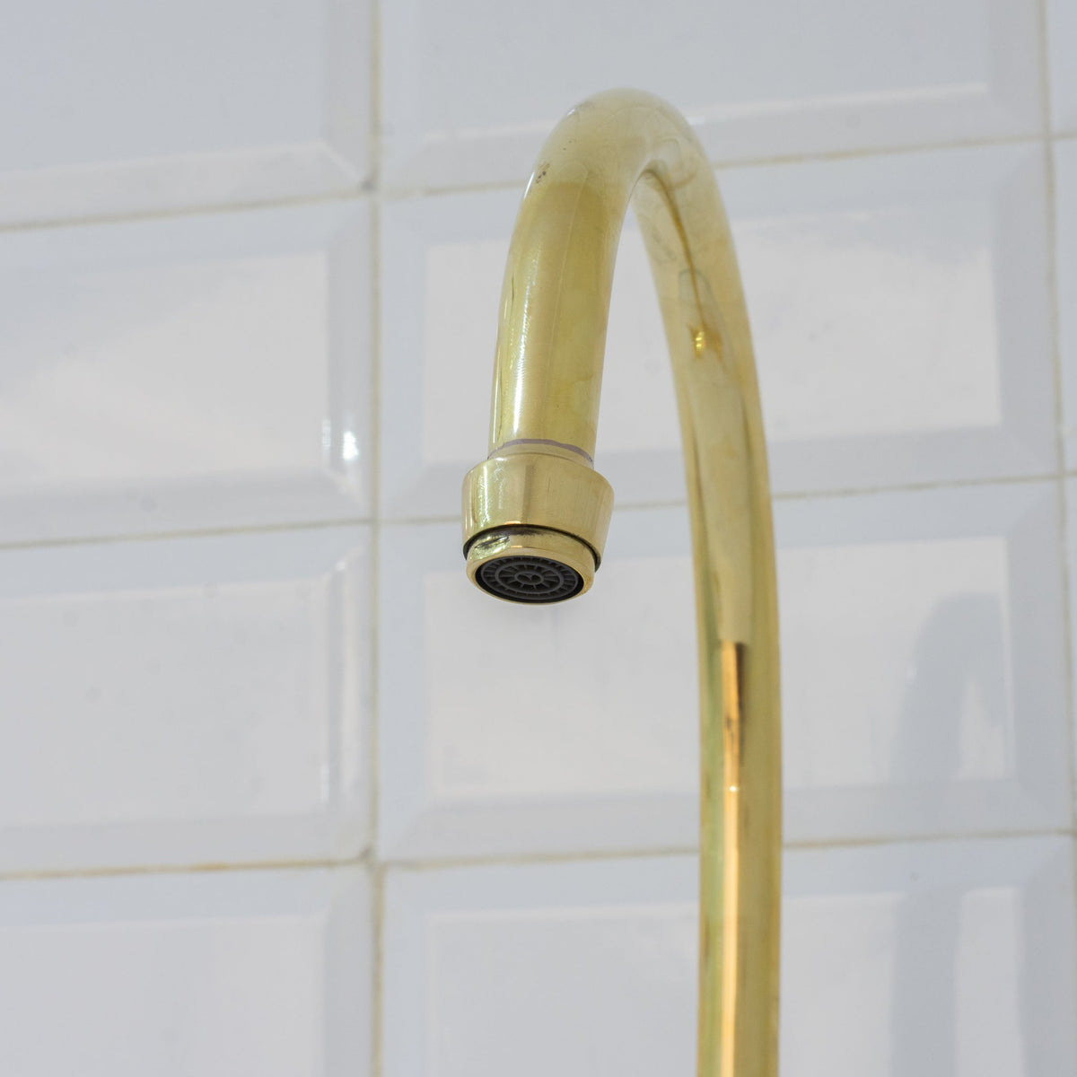 Close-up of the unlacquered brass bridge kitchen faucet swiveling spout