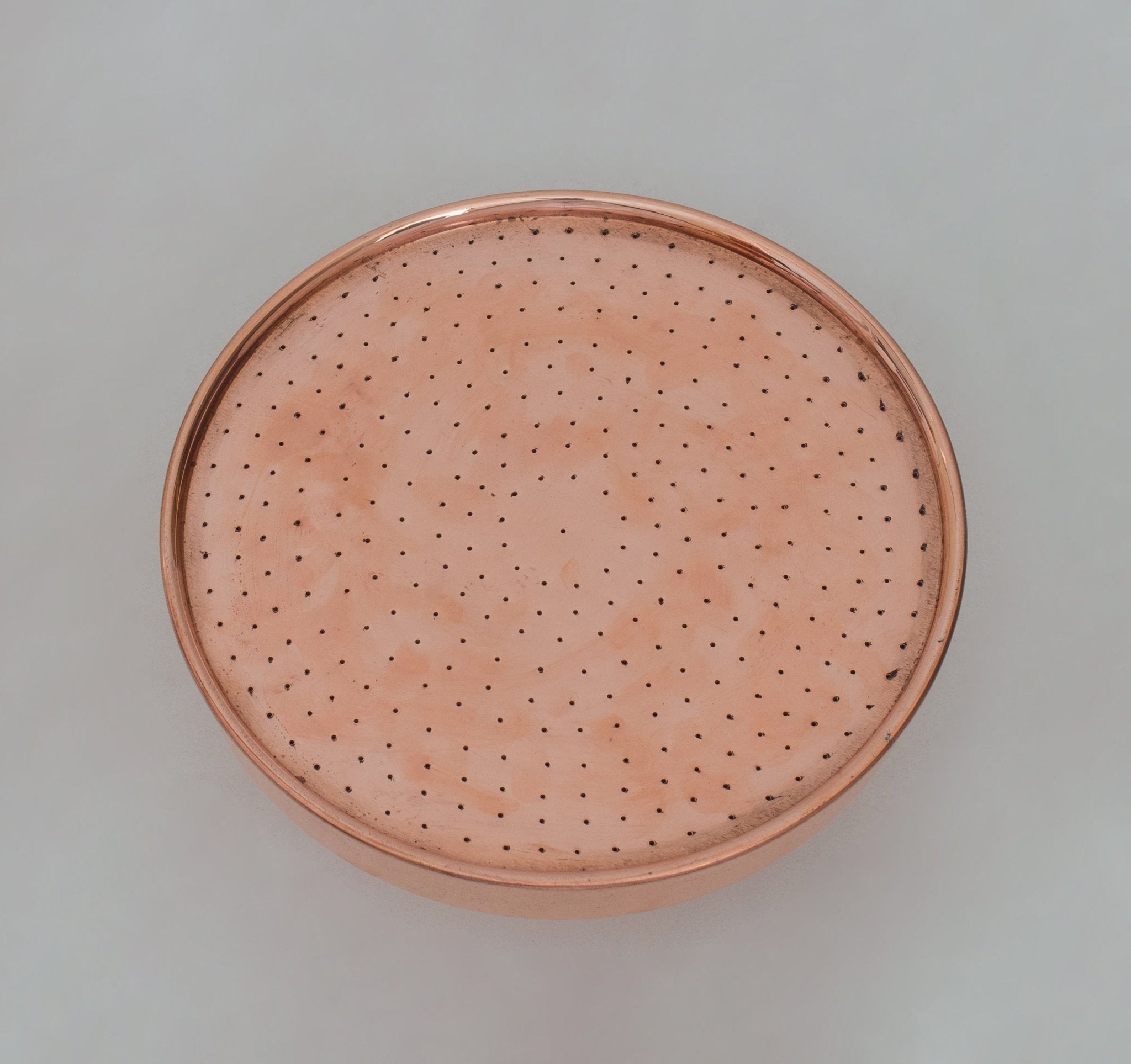 Copper rain shower head face detail showing spray holes